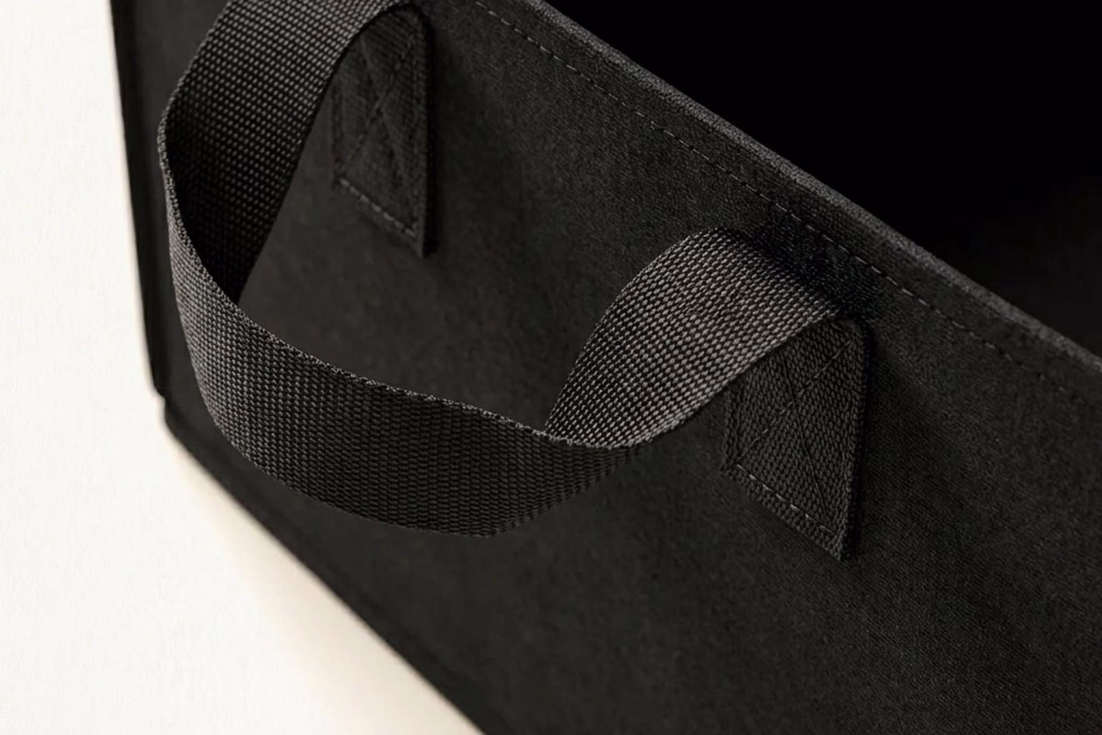 Macro sur une poignee laterale en sangle nylon noire avec couture double renforcee sur le tissu geotextile