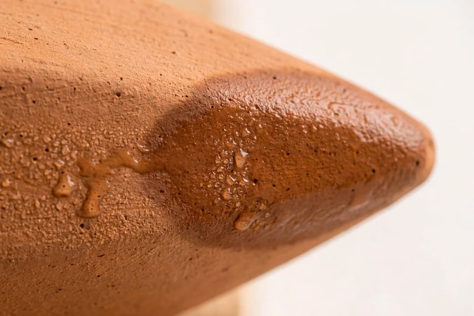 Macro de la paroi exterieure d'une oya en terre cuite avec aureole d'humidite visible et gouttes de condensation a travers la microporosite