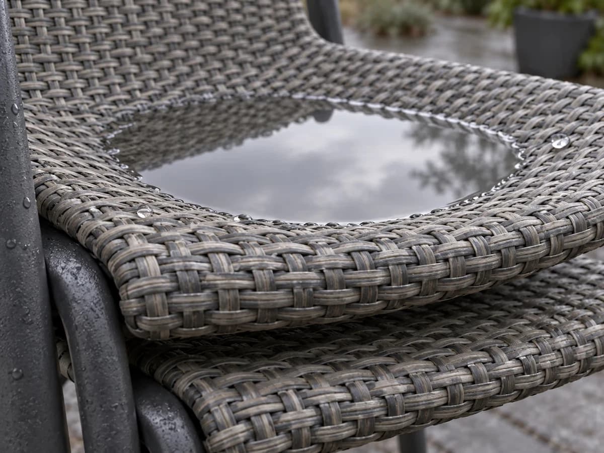 Gros plan du creux d'une assise de chaise de jardin où une flaque reste prise entre deux sièges empilés