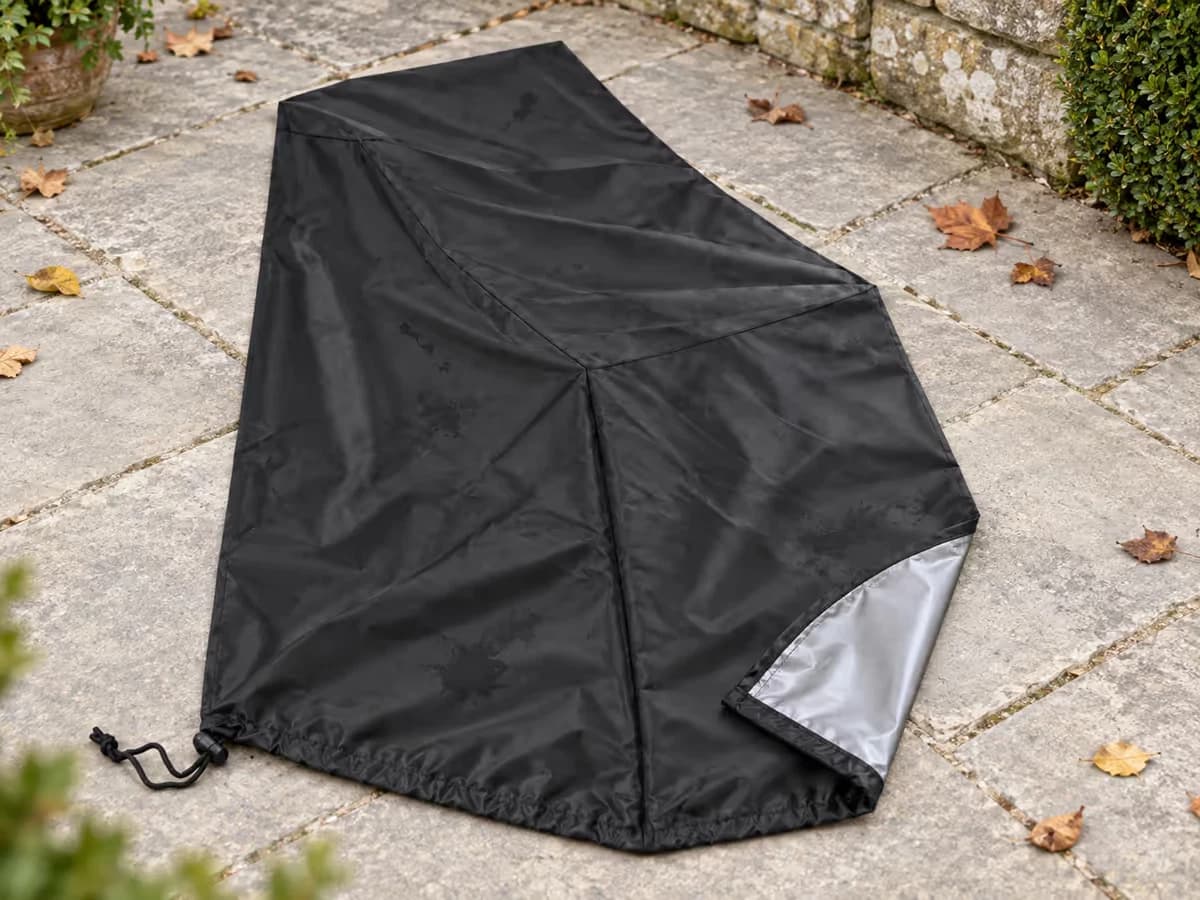 Housse de protection noire étalée à plat sur une terrasse pour sécher, enduit argenté visible sur la face interne retournée