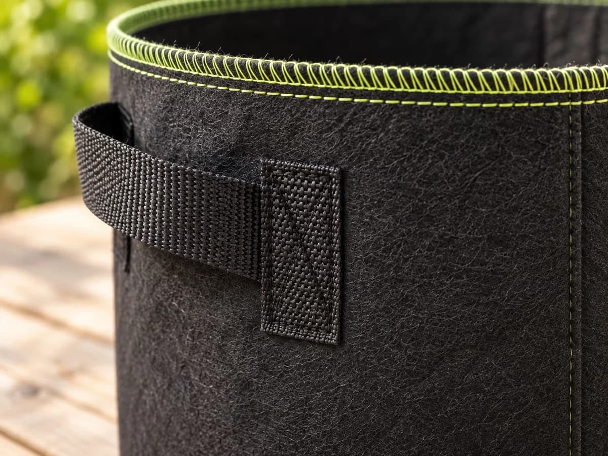 Macro sur une poignée latérale en sangle noire cousue en double point sur un pot en tissu noir avec surpiqûre vert clair