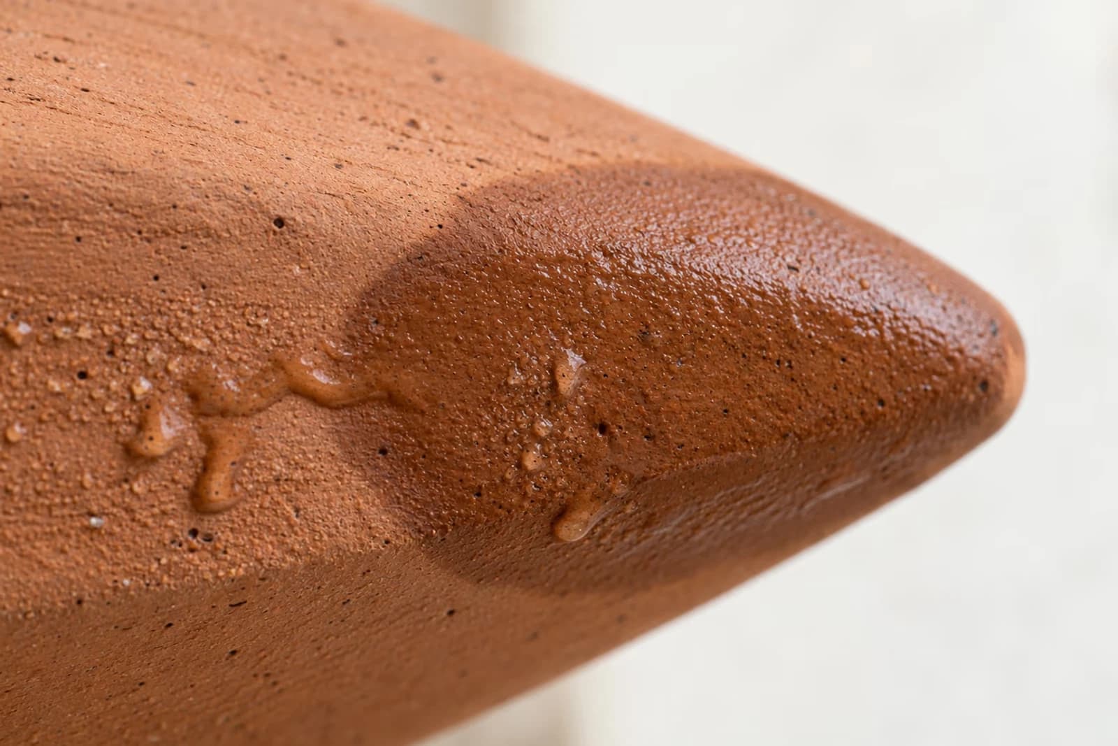 Macro de la paroi exterieure d'une oya en terre cuite avec aureole d'humidite visible et gouttes de condensation a travers la microporosite