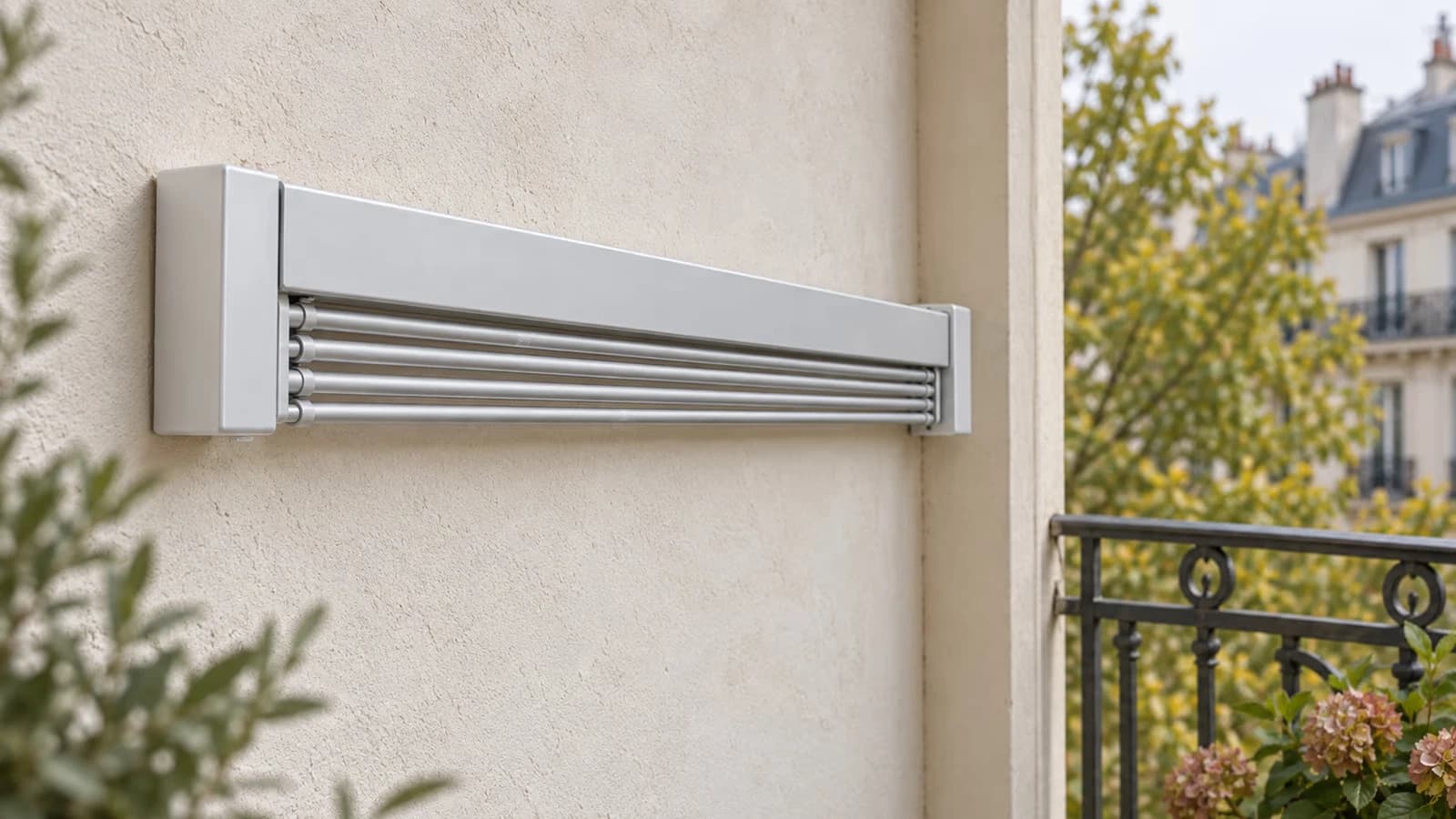 Étendoir mural en aluminium replié contre le mur d'un balcon, garde-corps en arrière-plan, une barre portant une marque claire