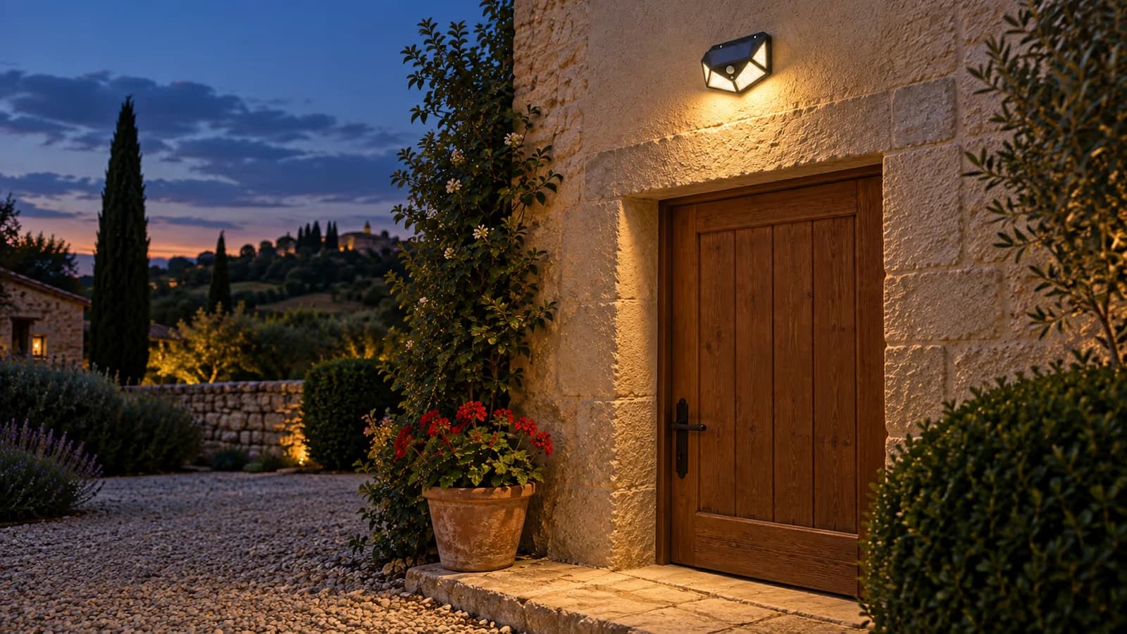 Lampe solaire noire à facettes fixée au-dessus d'une porte d'entrée, faisceau descendant sur le seuil à la tombée du jour