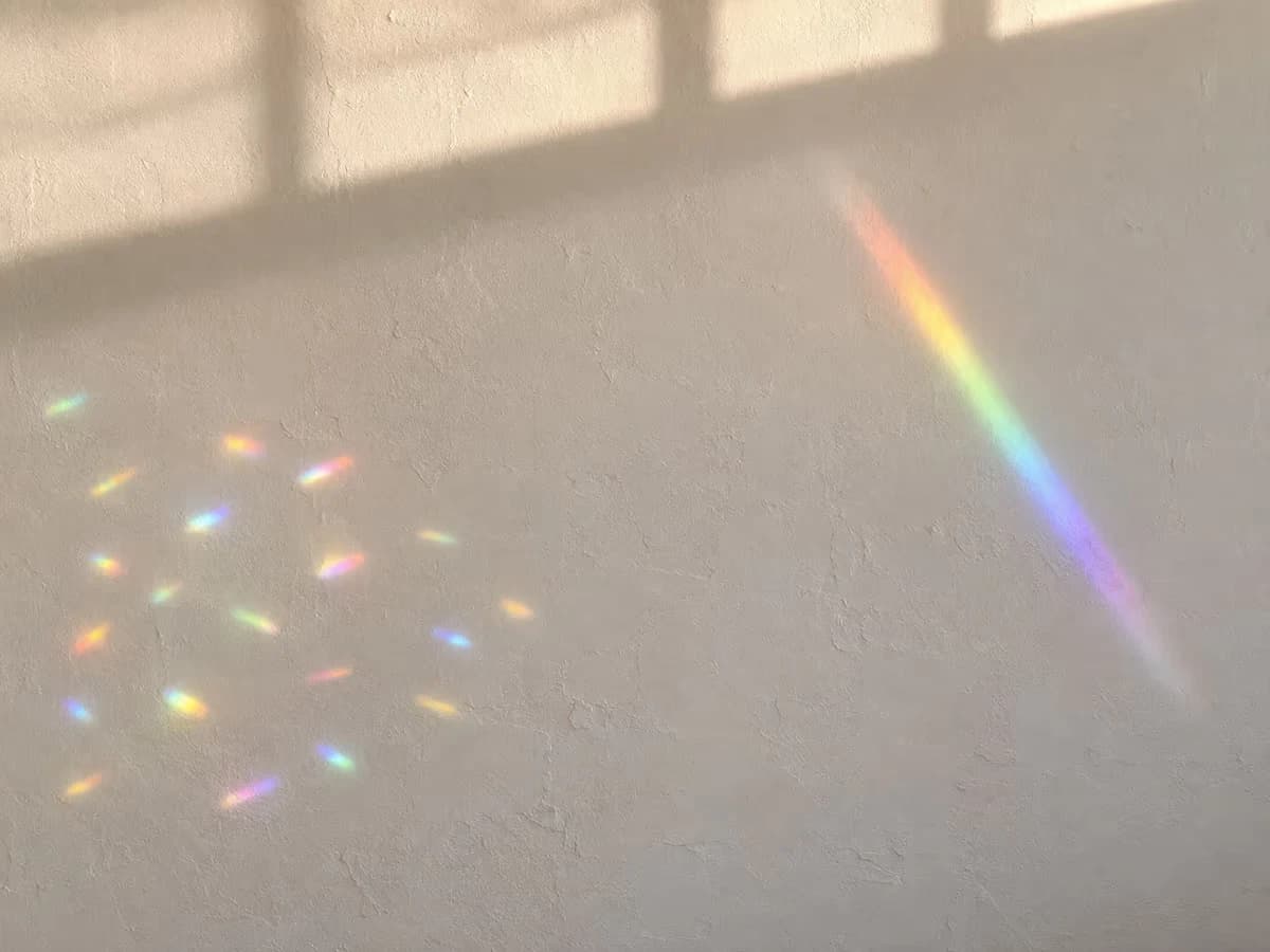 Taches colorées courtes dispersées sur un mur derrière un disque taillé, à côté d'une bande continue projetée par un prisme