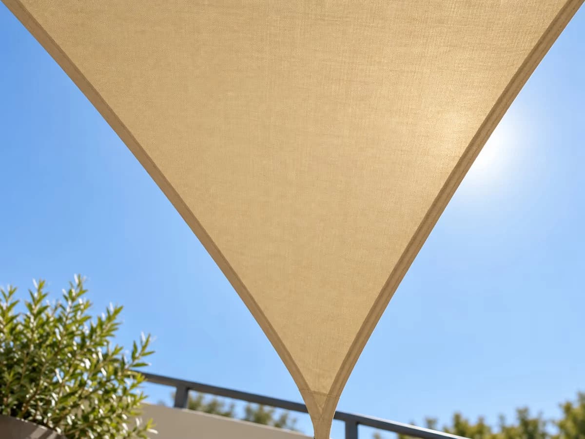 Voile d'ombrage vue du dessous sur fond de ciel, bords tendus et côtés ouverts laissant voir le ciel