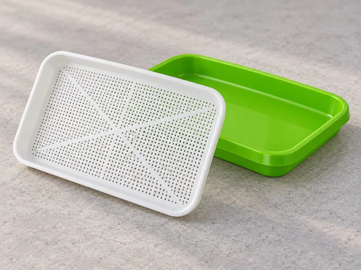 Insert à grille blanche sorti de son bac vert et posé de biais, petits trous de la grille visibles