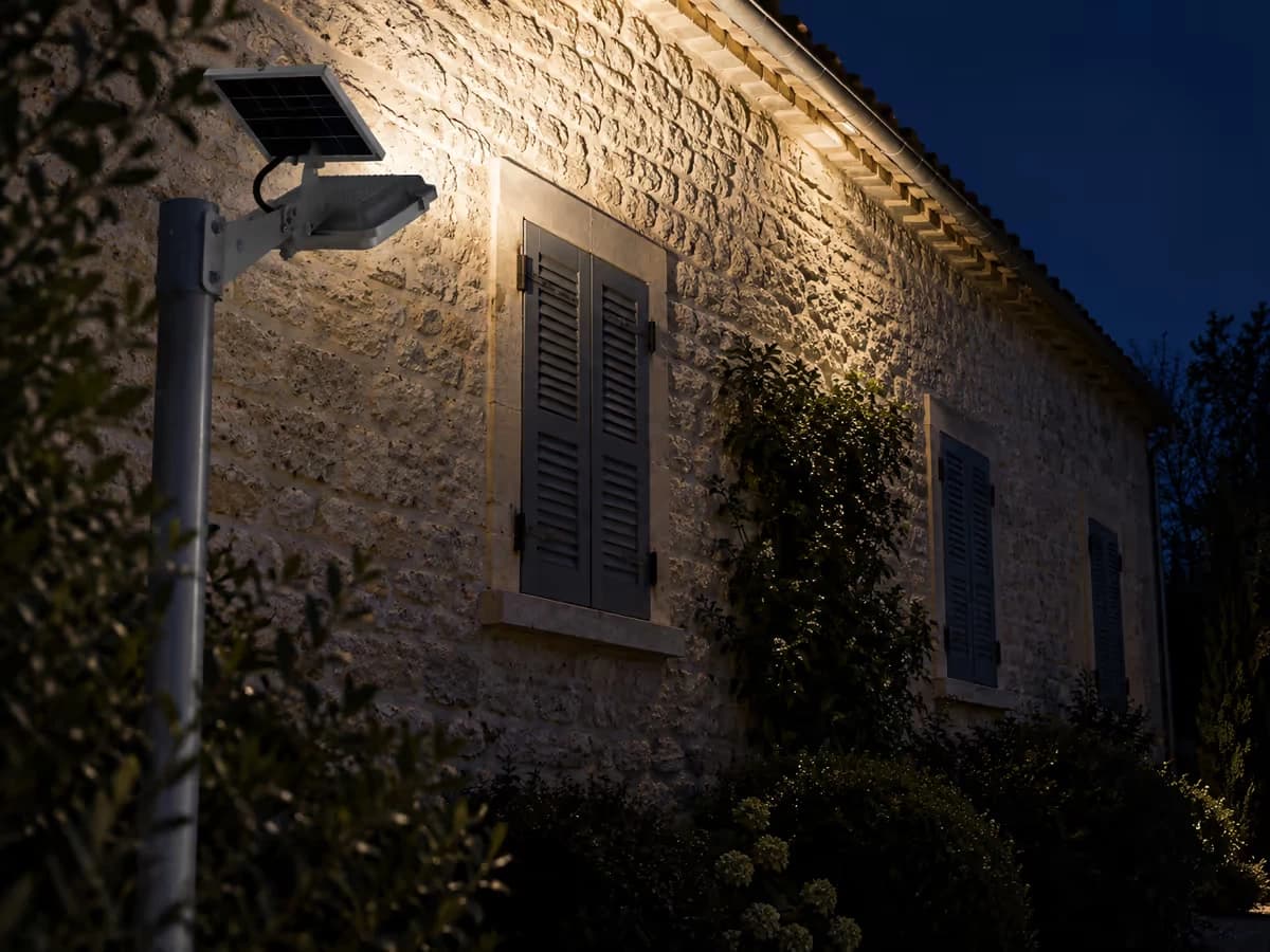 Façade éclairée de biais par un luminaire solaire, haut du mur lumineux et pied du mur dans l'ombre
