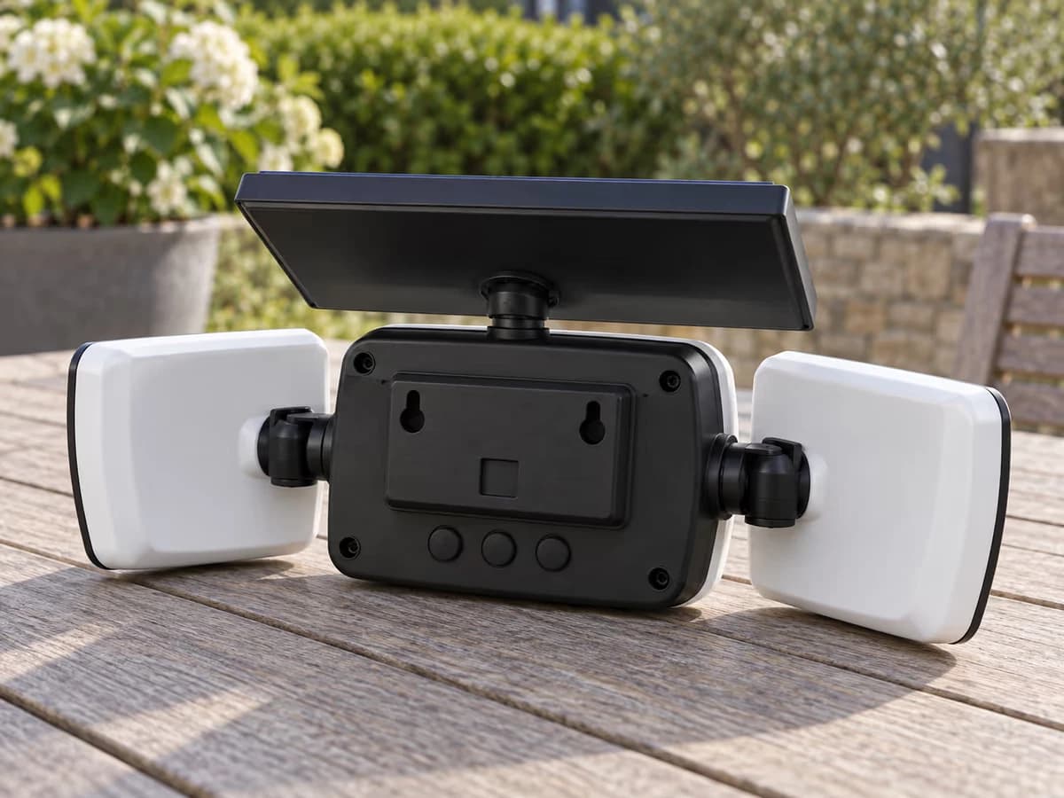 Dos d'une lampe solaire décrochée posée sur une table de jardin, boutons de réglage des modes visibles sous la platine de fixation