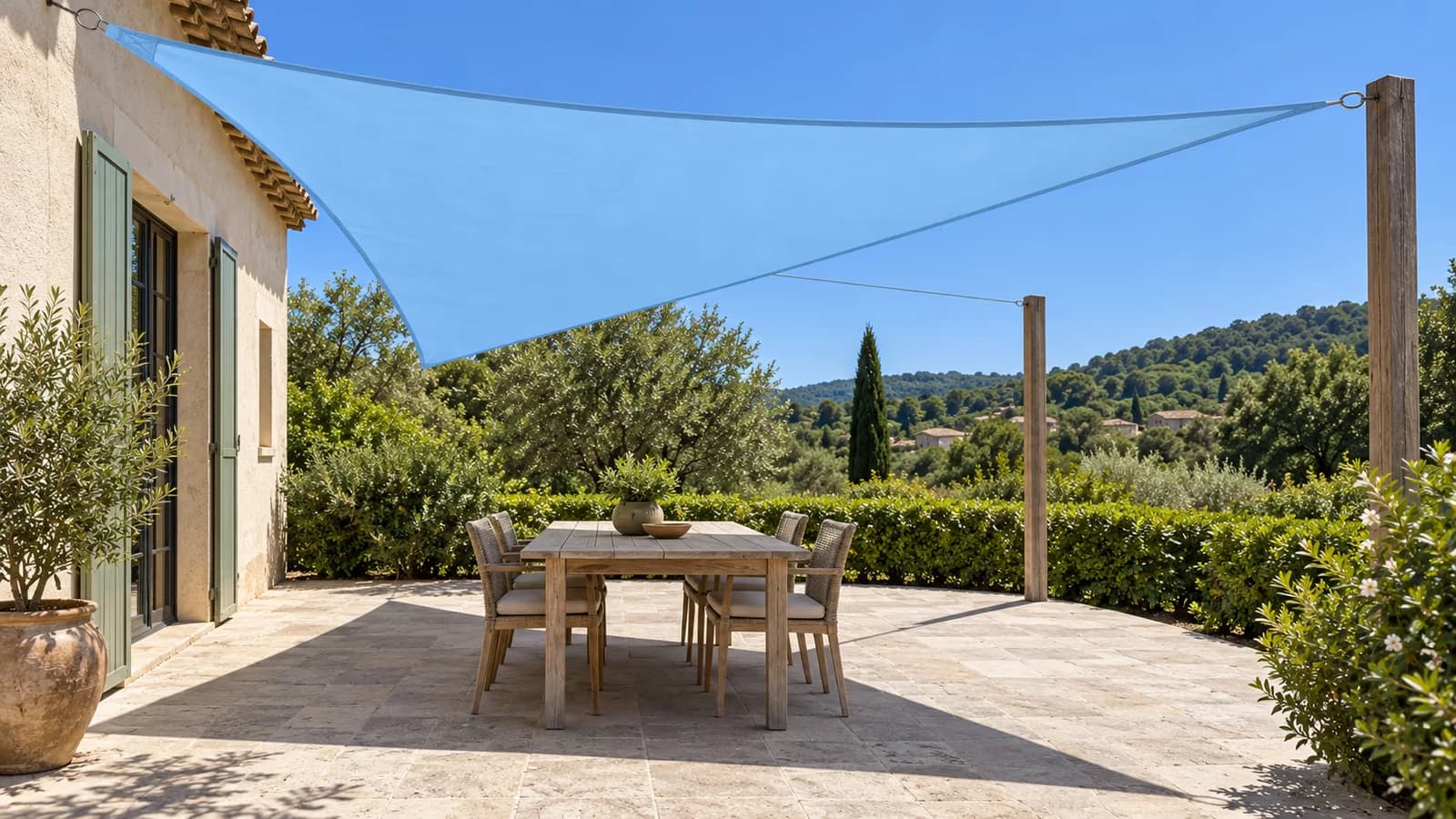Voile d'ombrage triangulaire bleu ciel tendue au-dessus d'une terrasse, ombre nette portée sur la dalle à midi