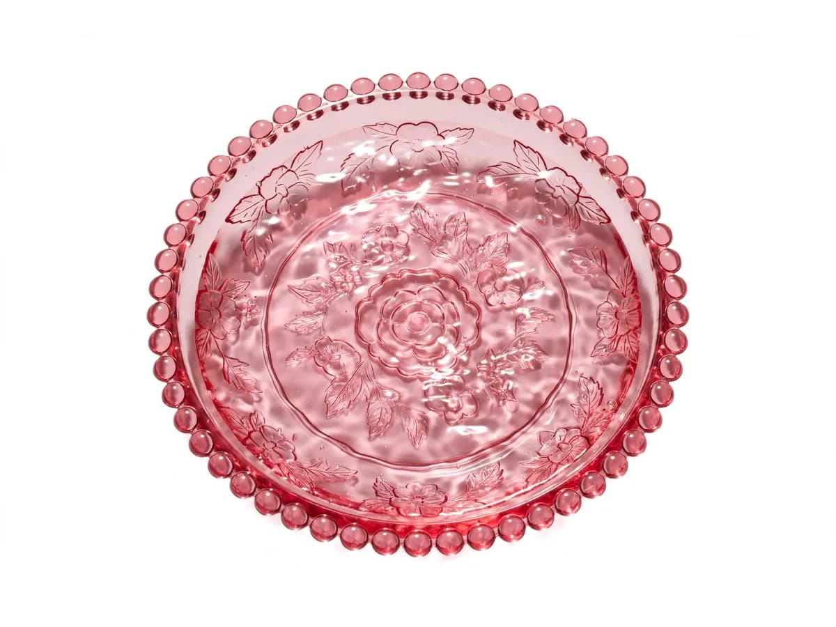 Gros plan de la coupelle vue du dessus avec un fond d'eau claire, bord festonné de perles moulées et motif floral gravé au fond