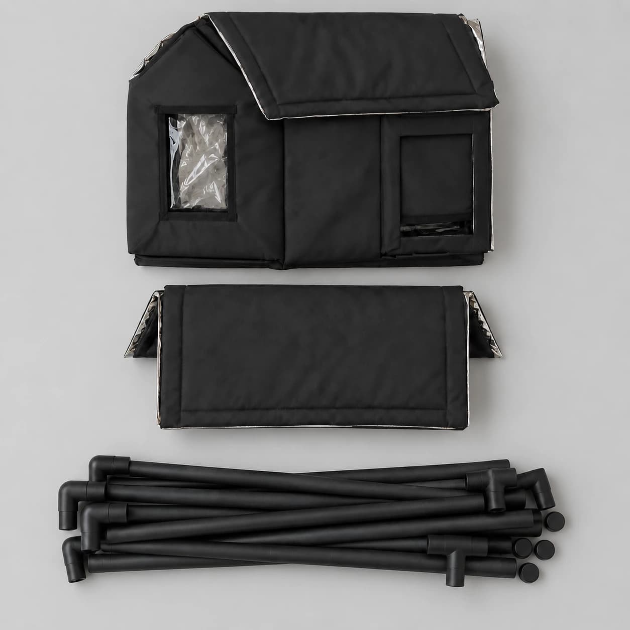 Contenu du colis à plat : enveloppe textile pliée, panneau de toit et faisceau de tubes noirs avec leurs raccords