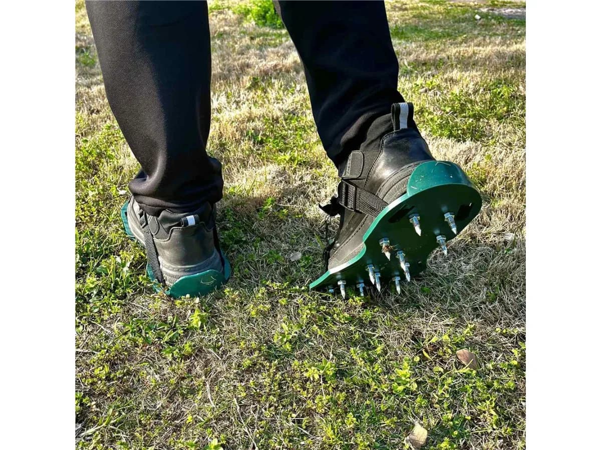 Un pied chaussé de la semelle avance sur la pelouse, pointes enfoncées dans l'herbe