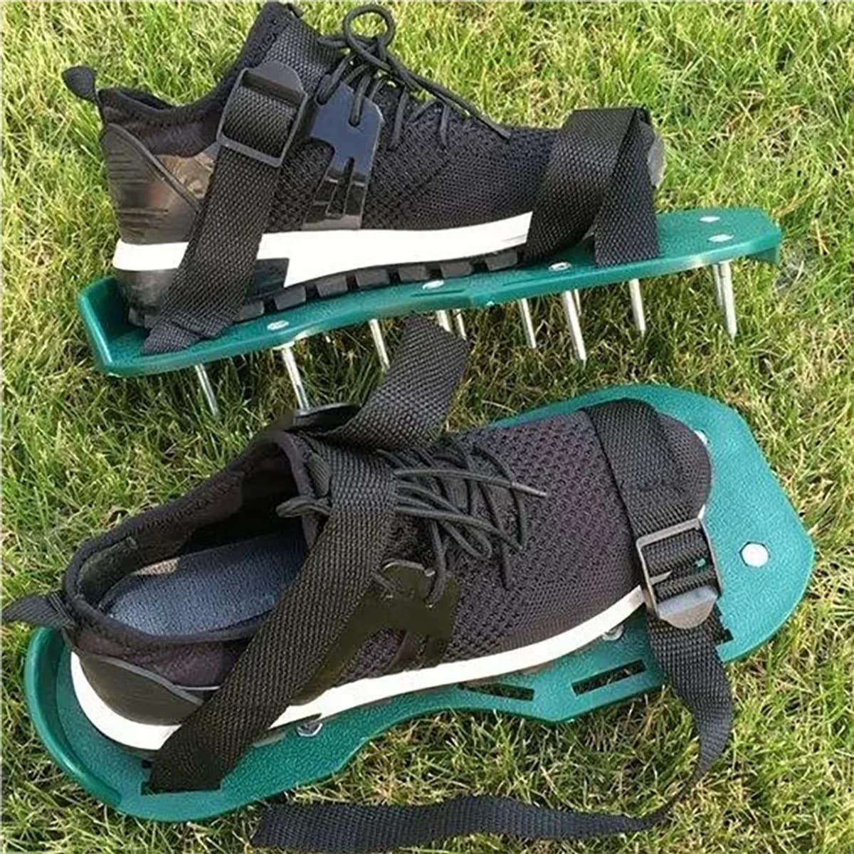 La paire sanglée sur des chaussures noires, posée sur une pelouse, semelles vertes, pointes en acier de profil et trois sangles à boucle métallique par pied
