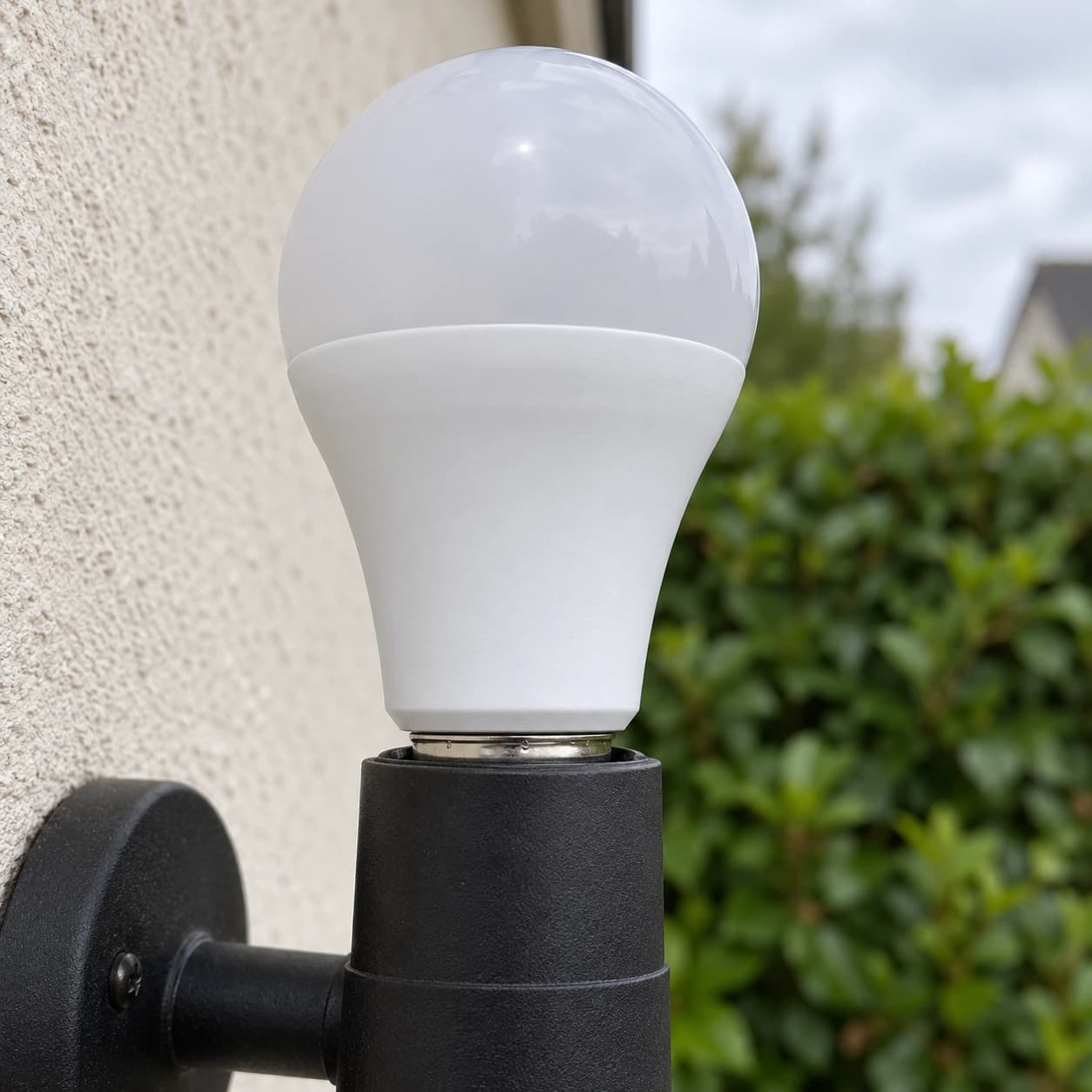 Ampoule E27 vissée dans une douille murale noire, à l'extérieur