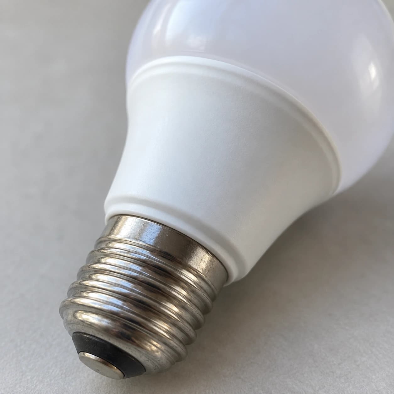 Gros plan sur le culot E27 fileté et le collier blanc vierge de l'ampoule radar