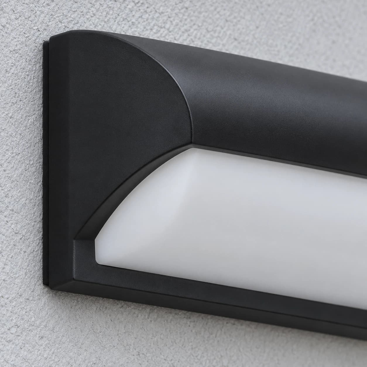 Le bout gauche de l'applique éteinte, capot noir mat et platine de fixation en tranche