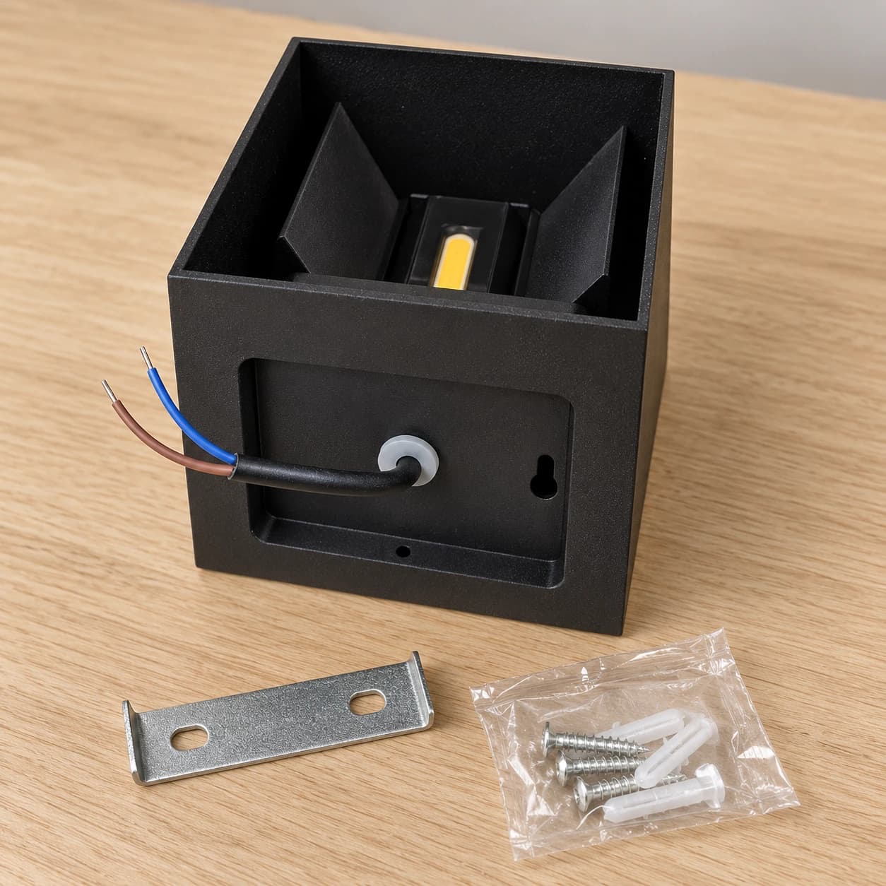 Le dos du cube noir, son presse-étoupe et ses fils, avec l'équerre de fixation et le sachet de vis