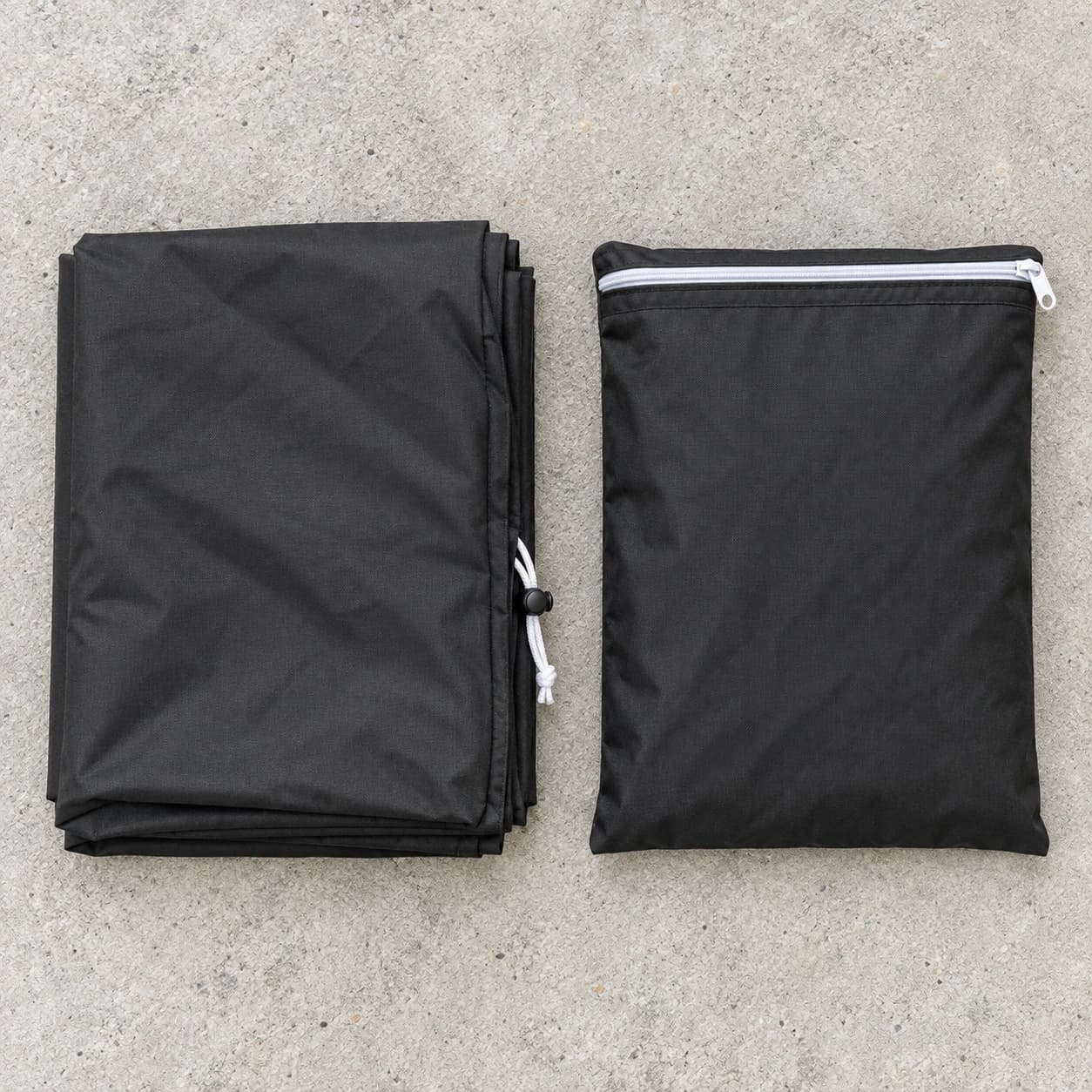 Contenu du colis à plat : housse pliée noir mat avec cordon et bloqueur, et sac de rangement zippé