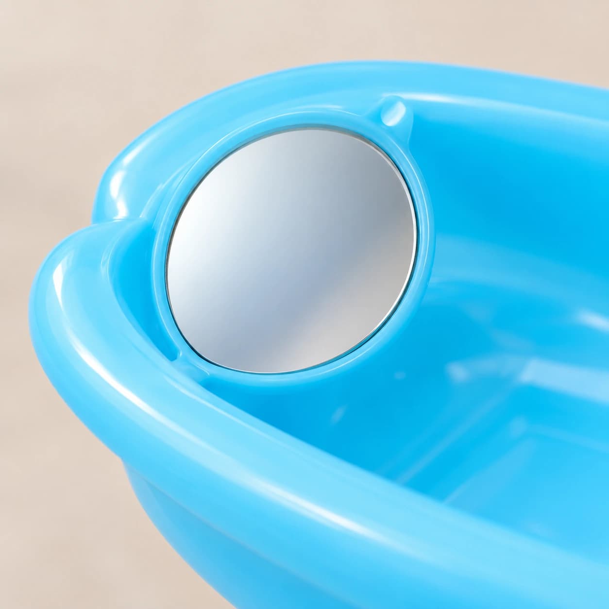 Le miroir rond du bol de bain, logé en biais dans sa collerette bleue