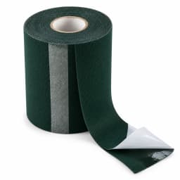 Le rouleau de bande de jonction vert foncé sur fond blanc, film blanc à demi décollé sur la face adhésive