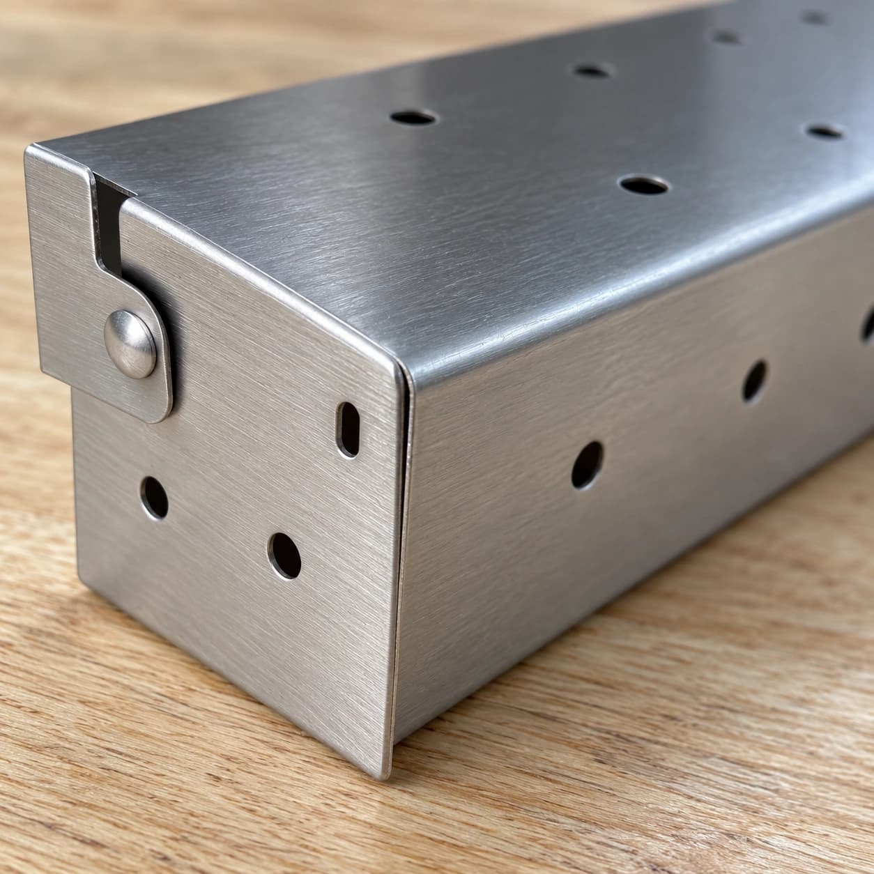 Gros plan sur le rivet de charnière et les perforations rondes du boîtier à copeaux en inox