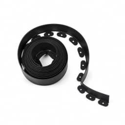 Rouleau de bordure de gazon noir enroulé en spirale serrée, pattes percées d'un trou rond, fond blanc