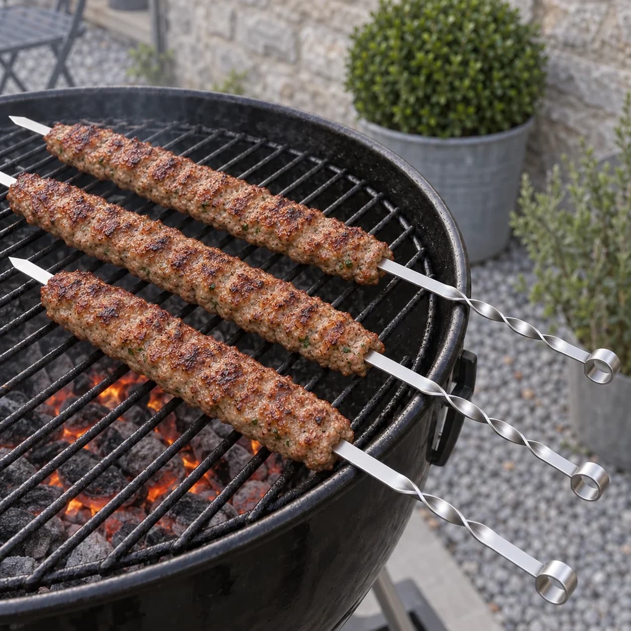 Brochettes de viande hachée façonnée en boudin en cuisson sur la grille d'un barbecue