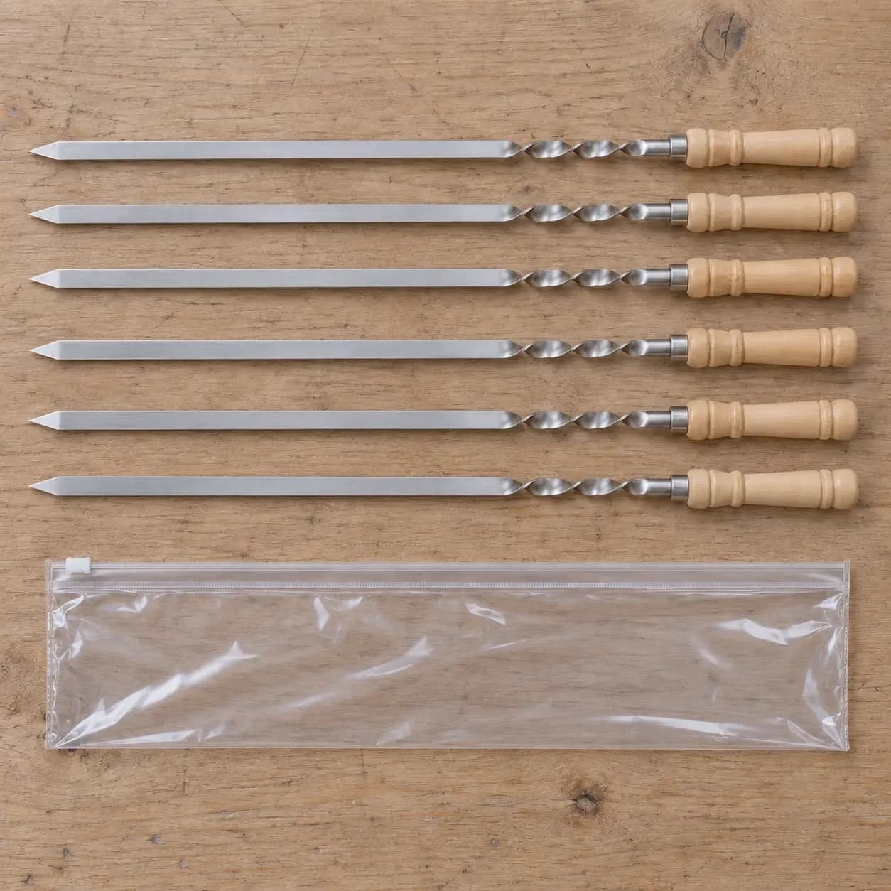 Lot de six brochettes alignées sur une table en bois clair avec la pochette transparente de livraison