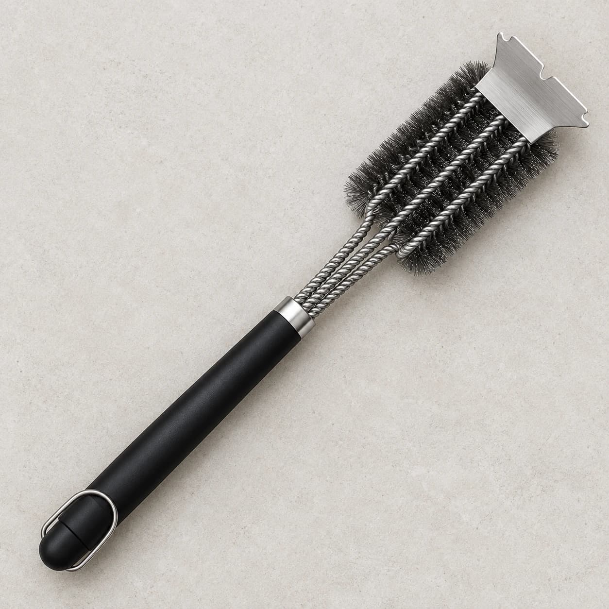 Contenu du colis, une brosse à gril inox à rouleaux avec son grattoir cranté intégré, posée à plat