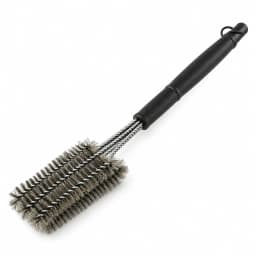 Brosse à gril à manche noir et tête à quatre rangs de spires d'acier, posée en diagonale sur fond blanc.