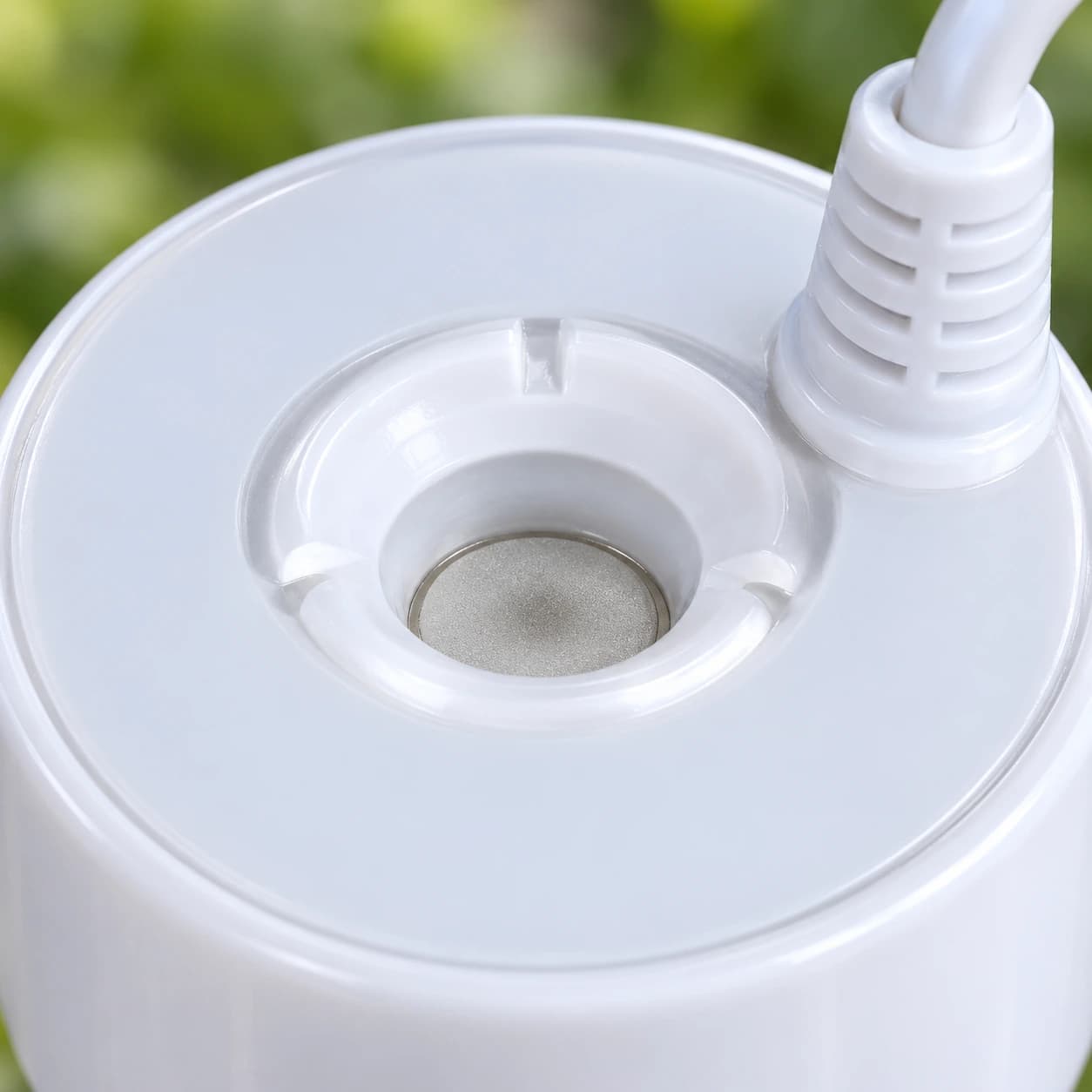 Détail de la face supérieure du brumisateur : entonnoir, pastille et presse-étoupe blanc
