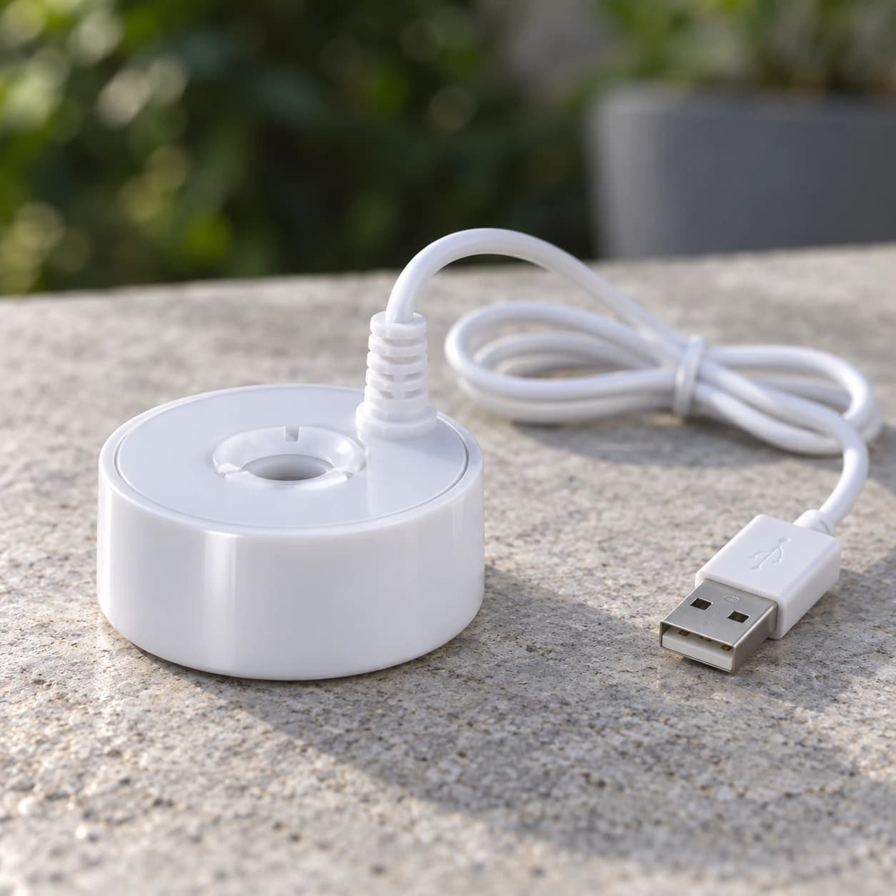 Vue de profil du brumisateur posé sur une pierre, épaisseur du disque et prise USB à l'échelle