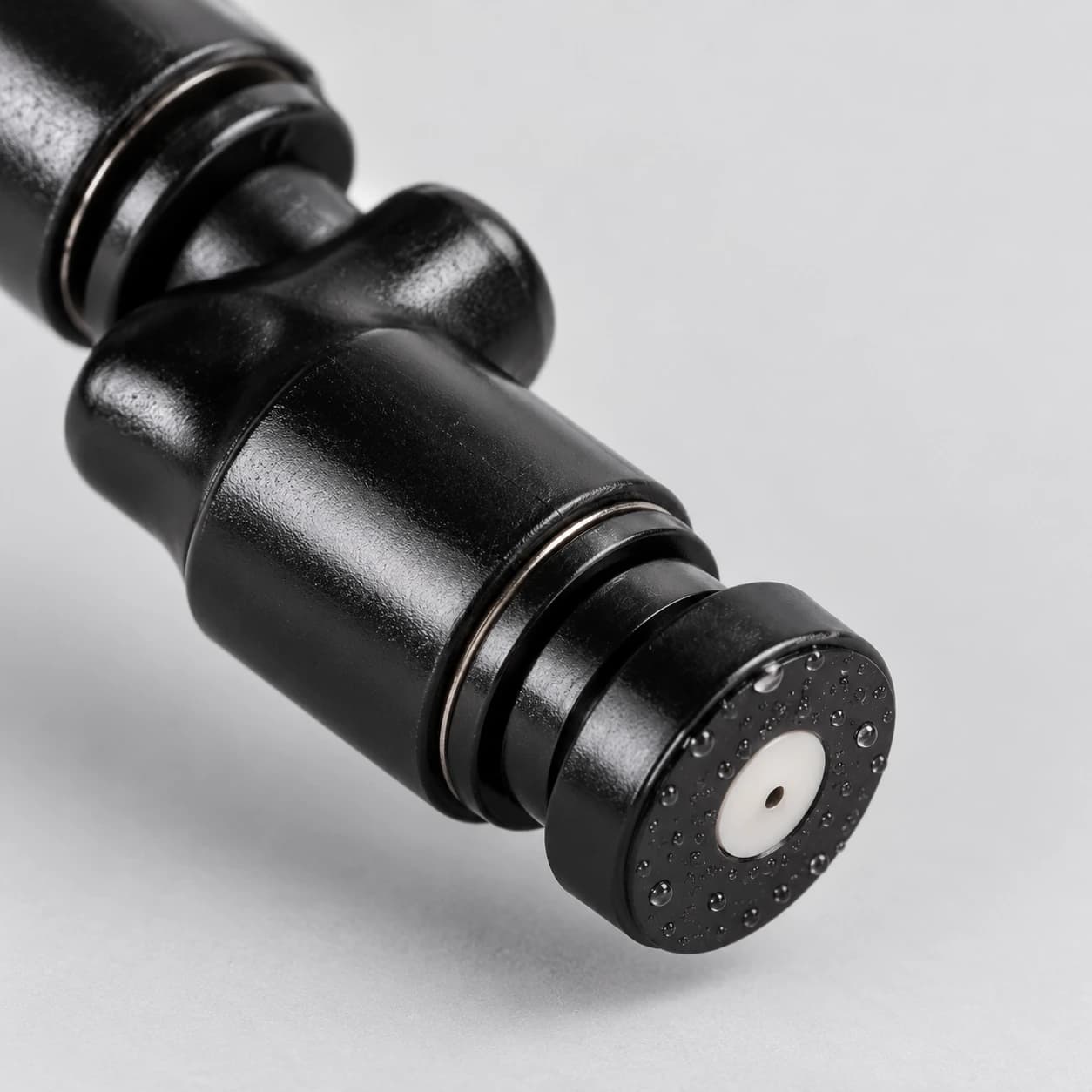 Gros plan de la face de la buse : bague claire et orifice central minuscule entourés de gouttelettes