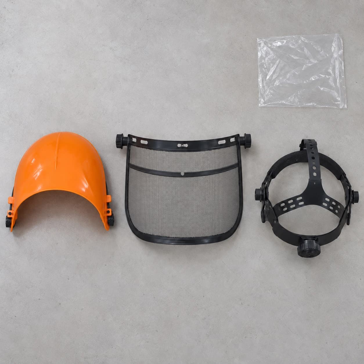 Le colis démonté : coque, visière grillagée et serre-tête posés à plat, avec le sachet