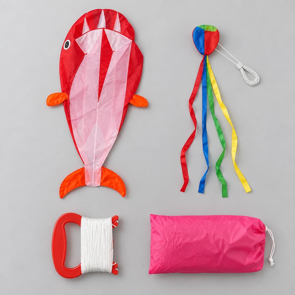Les quatre pièces du colis à plat : la voile, l'élément à rubans, la roue de ligne et le sac rose