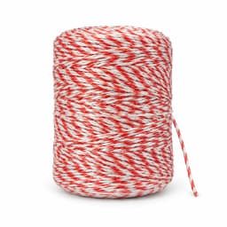 La bobine compacte de fil conducteur, corde rouge et blanche enroulée serré, sur fond blanc