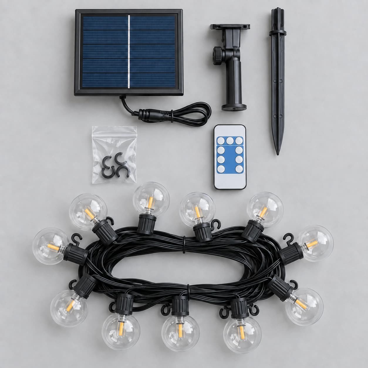 Contenu du colis à plat : ligne de onze globes lovée, panneau solaire et son piquet, télécommande, sachet de crochets