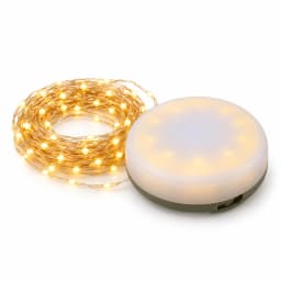 Packshot studio sur fond blanc de la lampe de camping ronde, dôme laiteux allumé et fil de 10 m enroulé en galette à côté