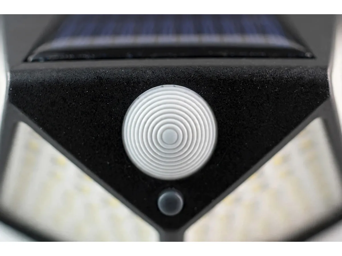 Macro de trois quarts sur la lentille ronde du détecteur et sur son bouton, arête vive des facettes latérales et grain de l'ABS noir mat