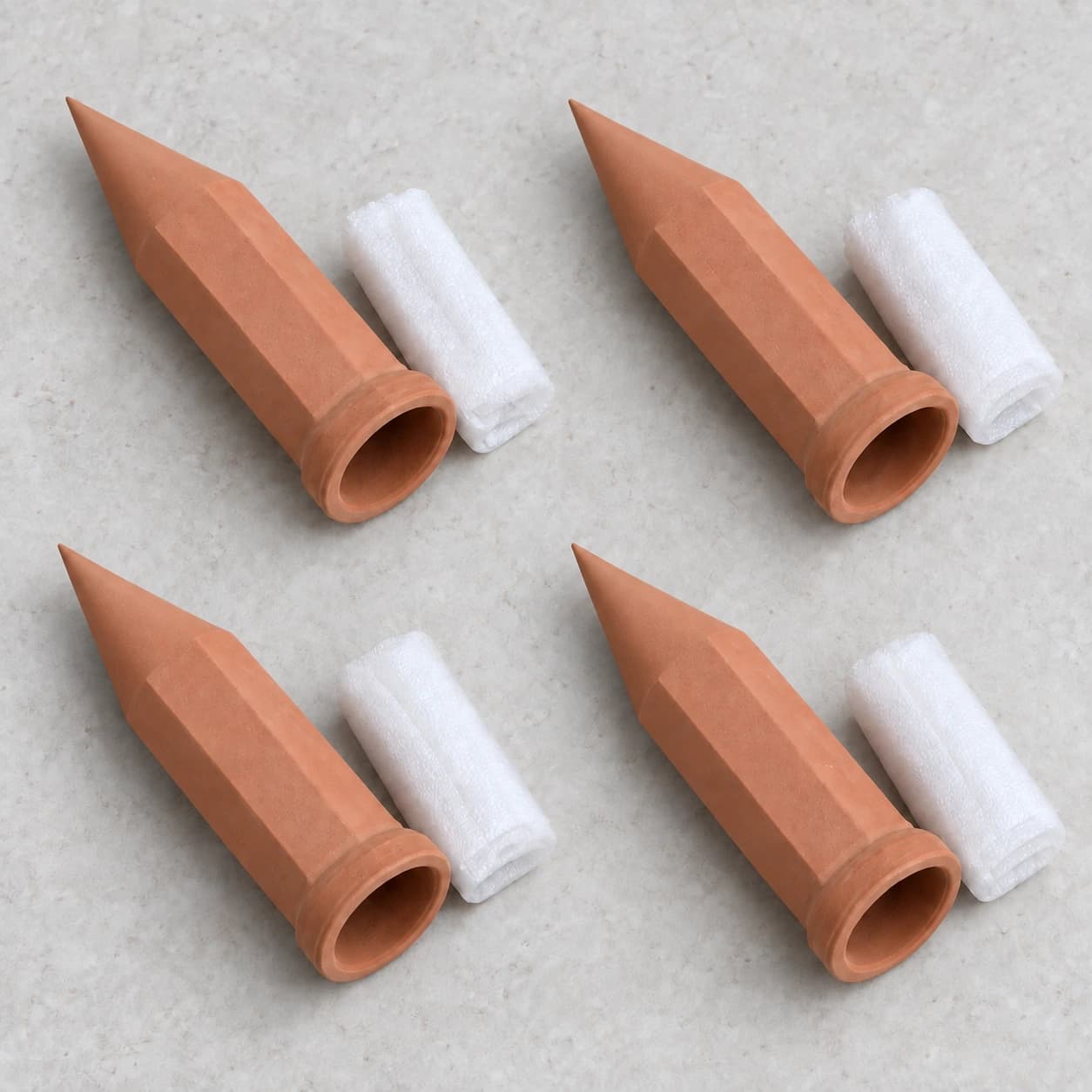 Quatre piques d'arrosage en terre cuite, chacune avec sa gaine de mousse protectrice