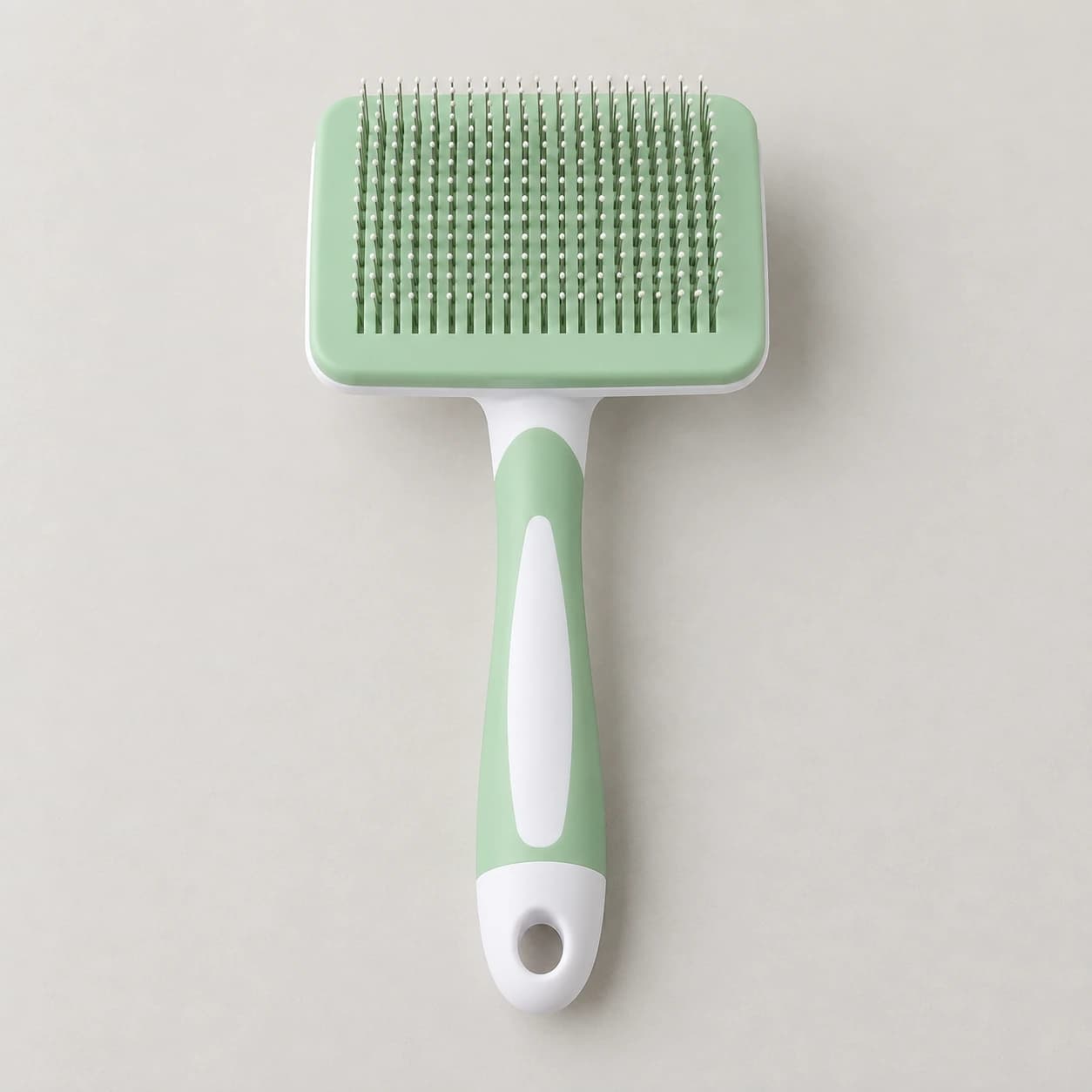 La brosse de toilettage verte livrée seule, posée à plat picots vers le haut