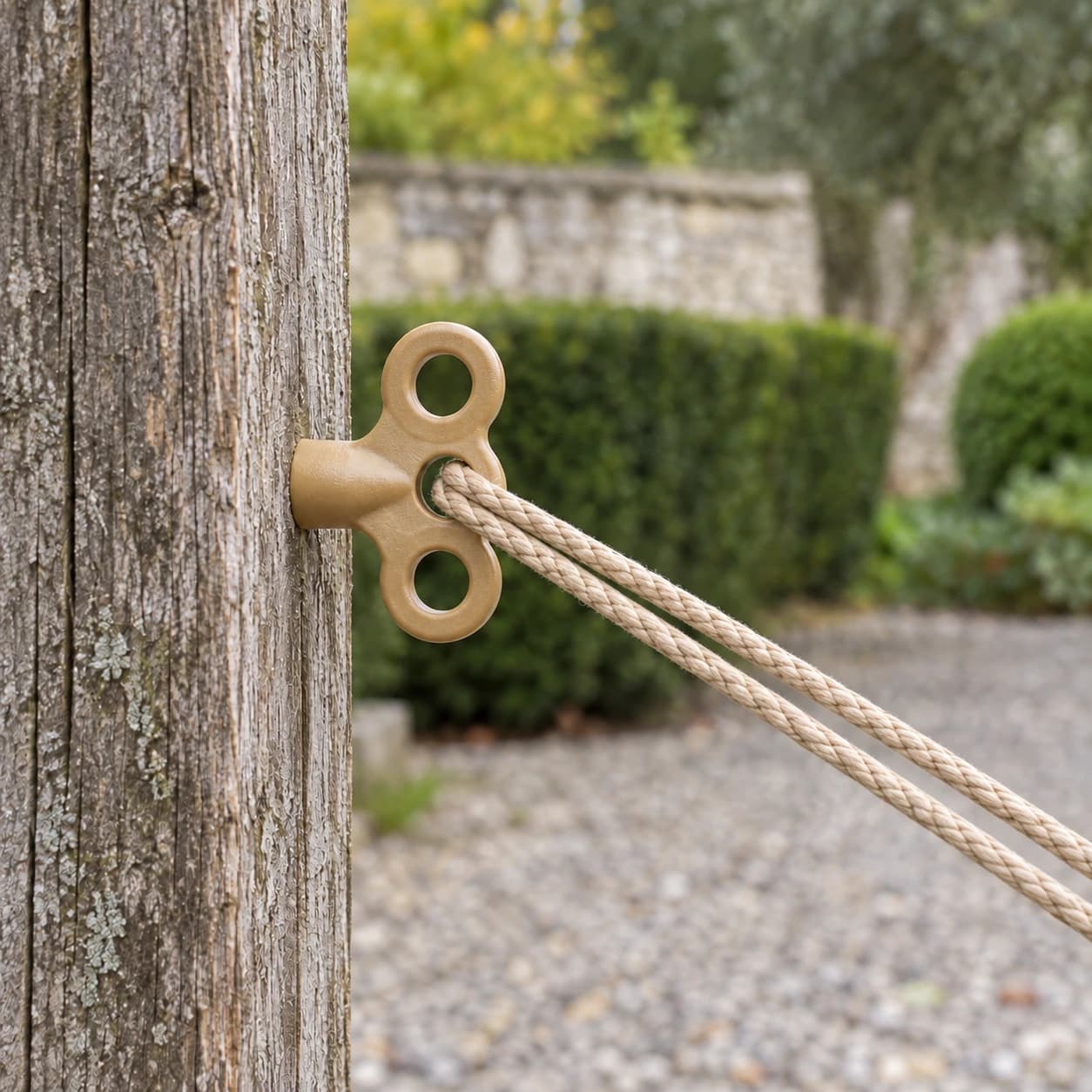 Le pieu vissé dans un poteau de bois au jardin, une corde beige tendue passant dans le trou central
