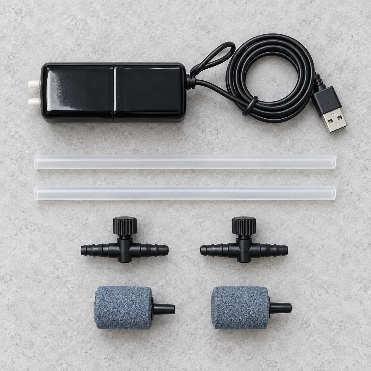 Contenu du kit posé à plat : pompe, câble USB, deux tuyaux, deux régulateurs et deux pierres diffusantes