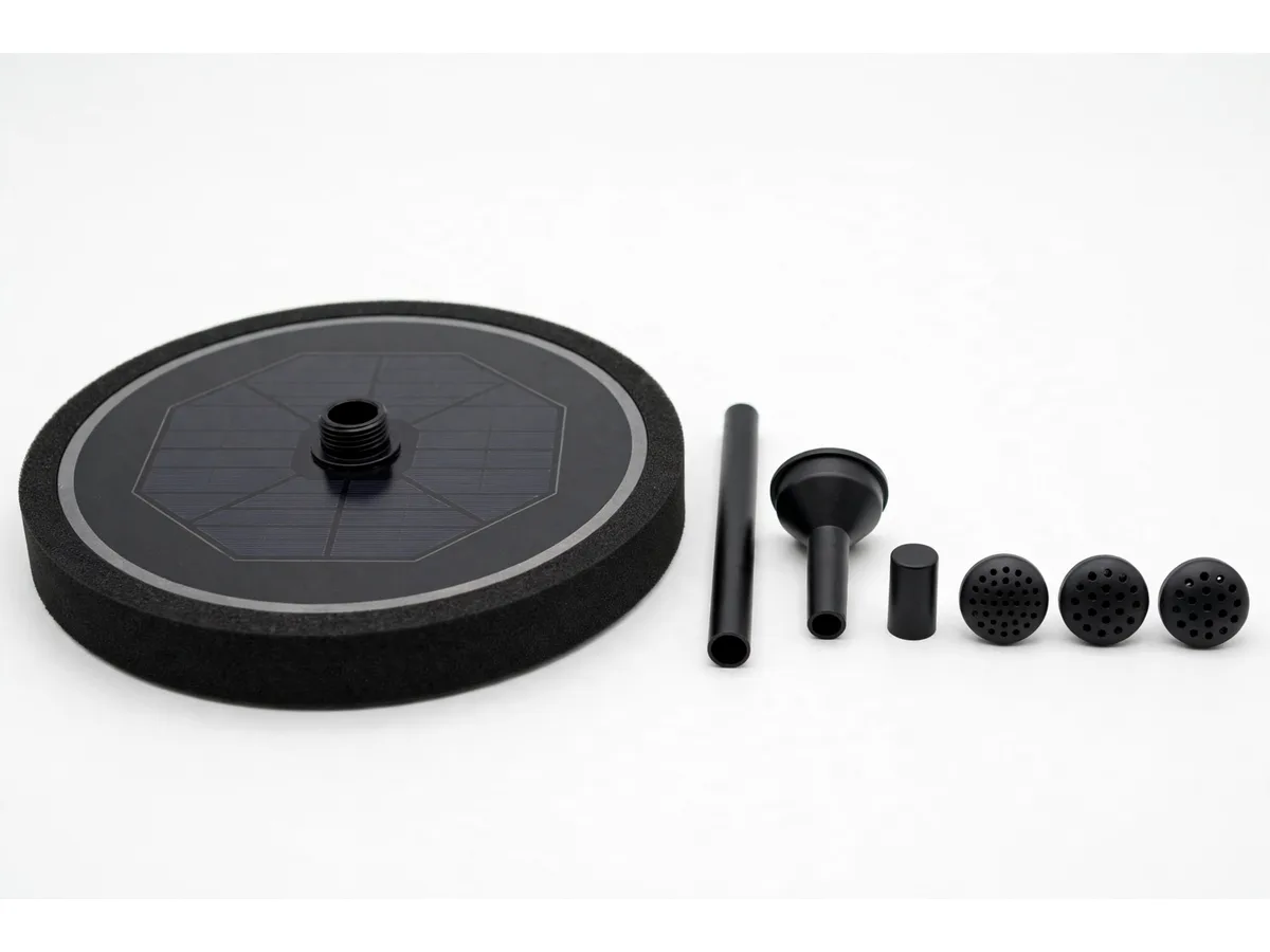 Le disque vu en plongée basse sur fond blanc, à côté de ses six accessoires noirs alignés, tube de rehausse, adaptateur entonnoir, bouchon et trois têtes
