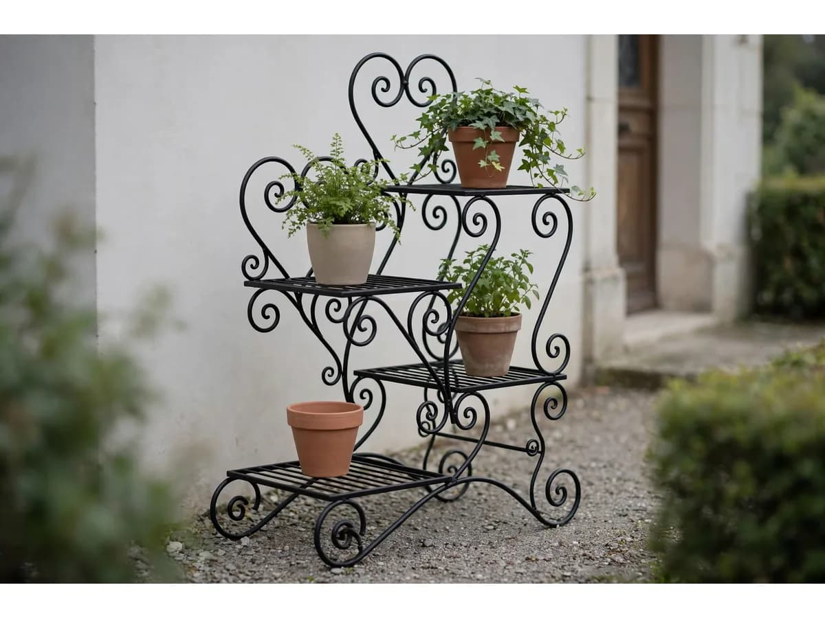 Porte plantes garni de quatre pots dont un lierre retombant, posé sur du gravier devant une entrée et un mur blanc