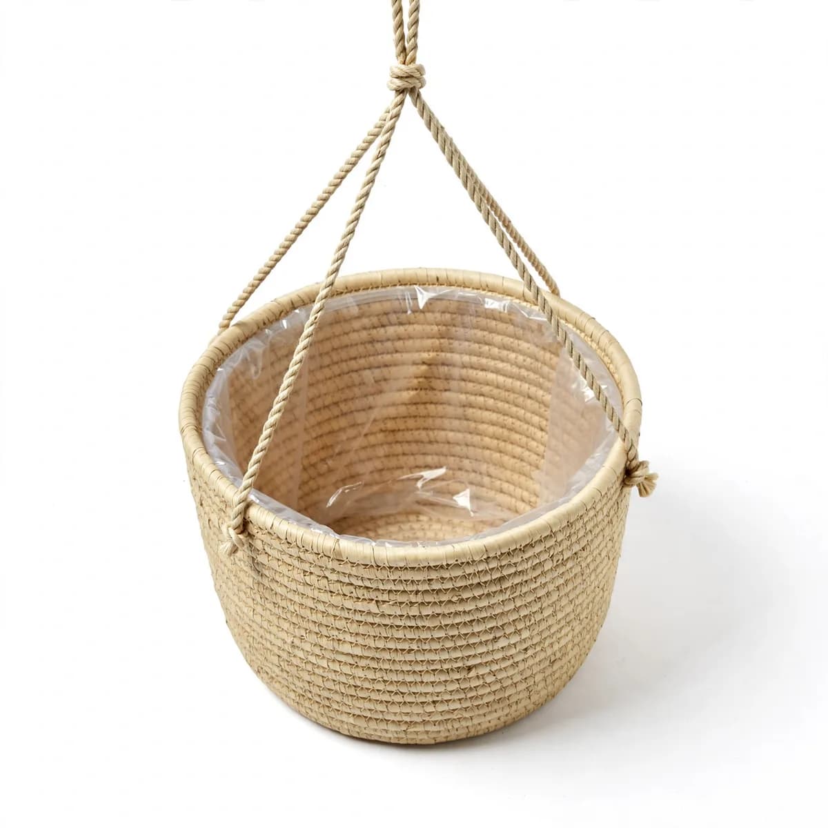 Panier suspendu tressé en fibre végétale beige, vide, porté par deux ficelles de coton nouées au-dessus, sur fond blanc