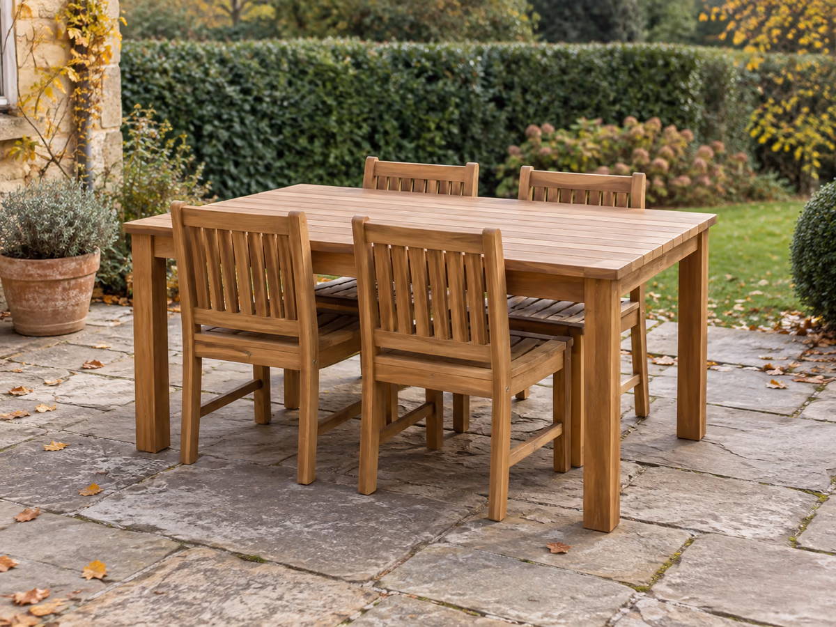 Chaises relevées et poussées sous une table de jardin rectangulaire en bois, vues de trois quarts sur terrasse