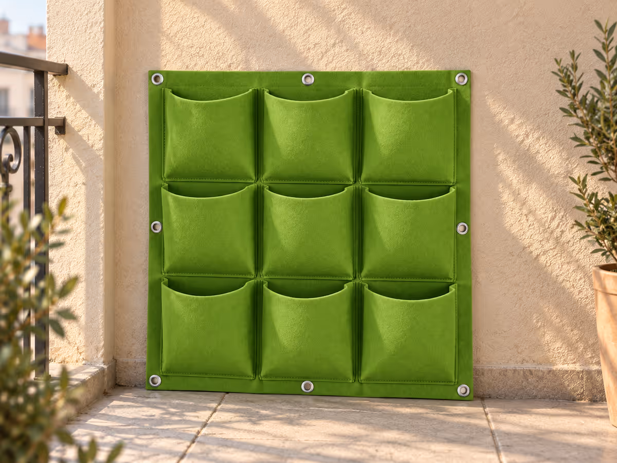 Panneau en feutre vide présenté à plat contre un mur de balcon baigné de soleil matinal, œillets métalliques visibles aux angles