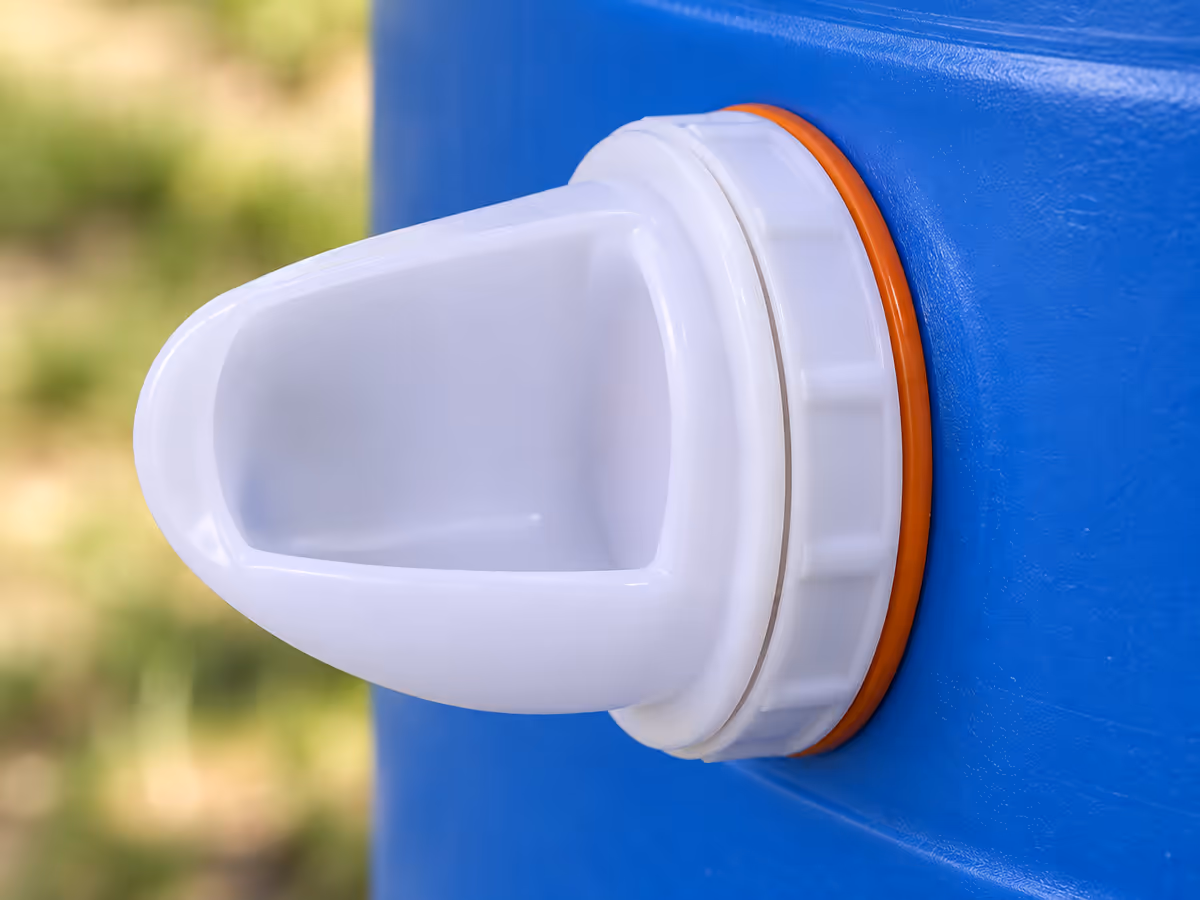 Gros plan d'un port blanc engagé dans la paroi percée d'un bidon, joint silicone orange logé entre le corps et la bague, paroi propre sans copeau